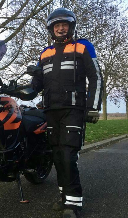 Foto van motorinstructeur in motorkleding naast motor